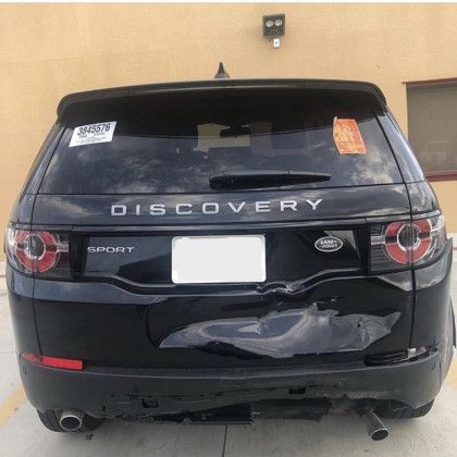 A black land rover discovery sport is parked in a parking lot.