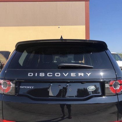 A black land rover discovery sport is parked in front of a building.