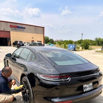 A man is changing a tire on a black sports car.