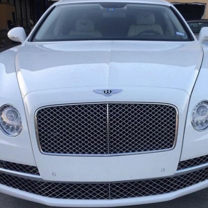 A white bentley is parked in a garage.