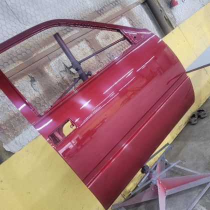 A red car door is sitting on a yellow table.
