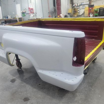 A truck bed is sitting on a cart in a garage.