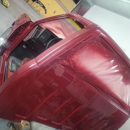 A red car is sitting on the ground in a garage.