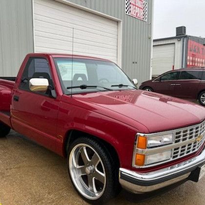 A red truck is parked in front of a garage.