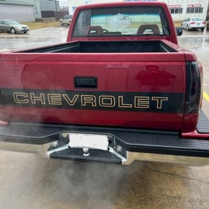 A red chevrolet truck is parked in a parking lot.