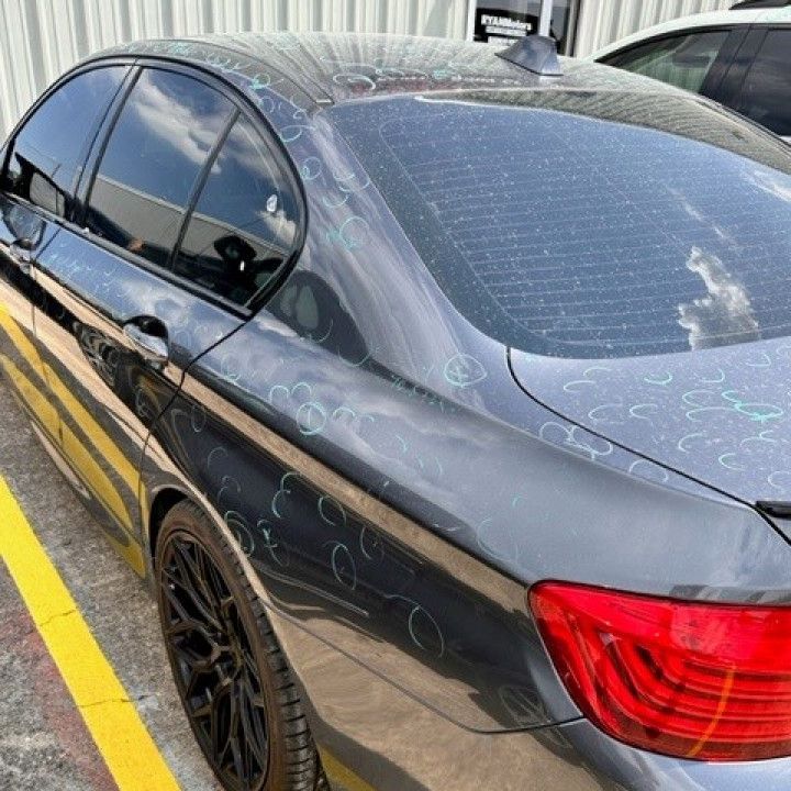 A black car with a red tail light is parked in a parking lot.