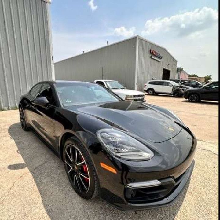 A black porsche panamera is parked in front of a building.