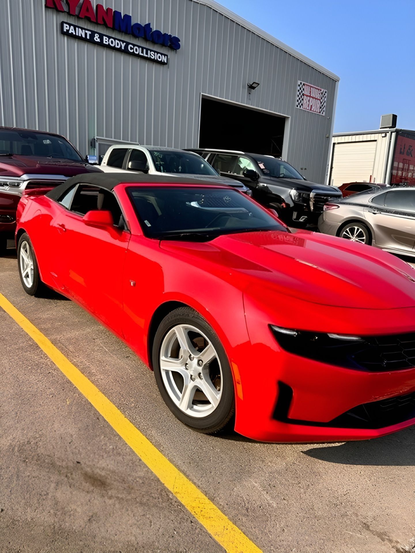 A red car is parked in a parking lot in front of a building after being repaired.