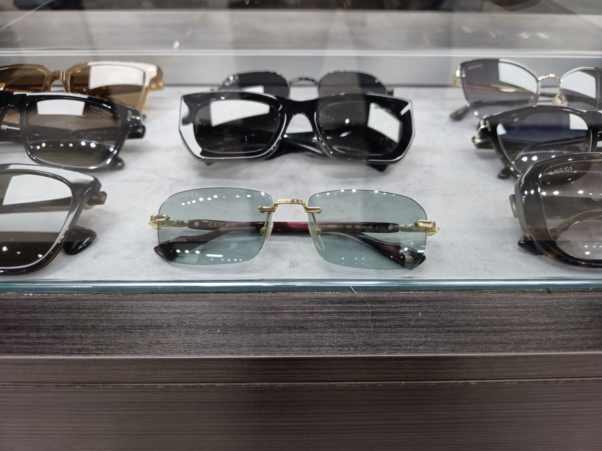 Sunglasses displayed in a store showcase with gold and black frames, various styles.