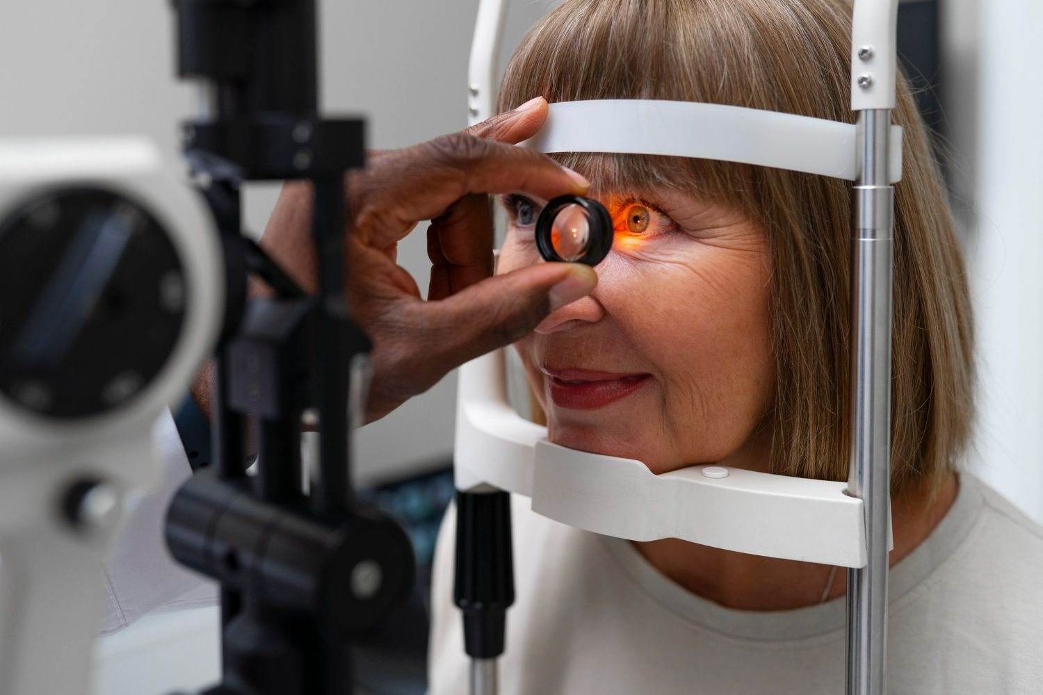 Optometrist examining a patient's eye with a slit lamp in a medical office.
