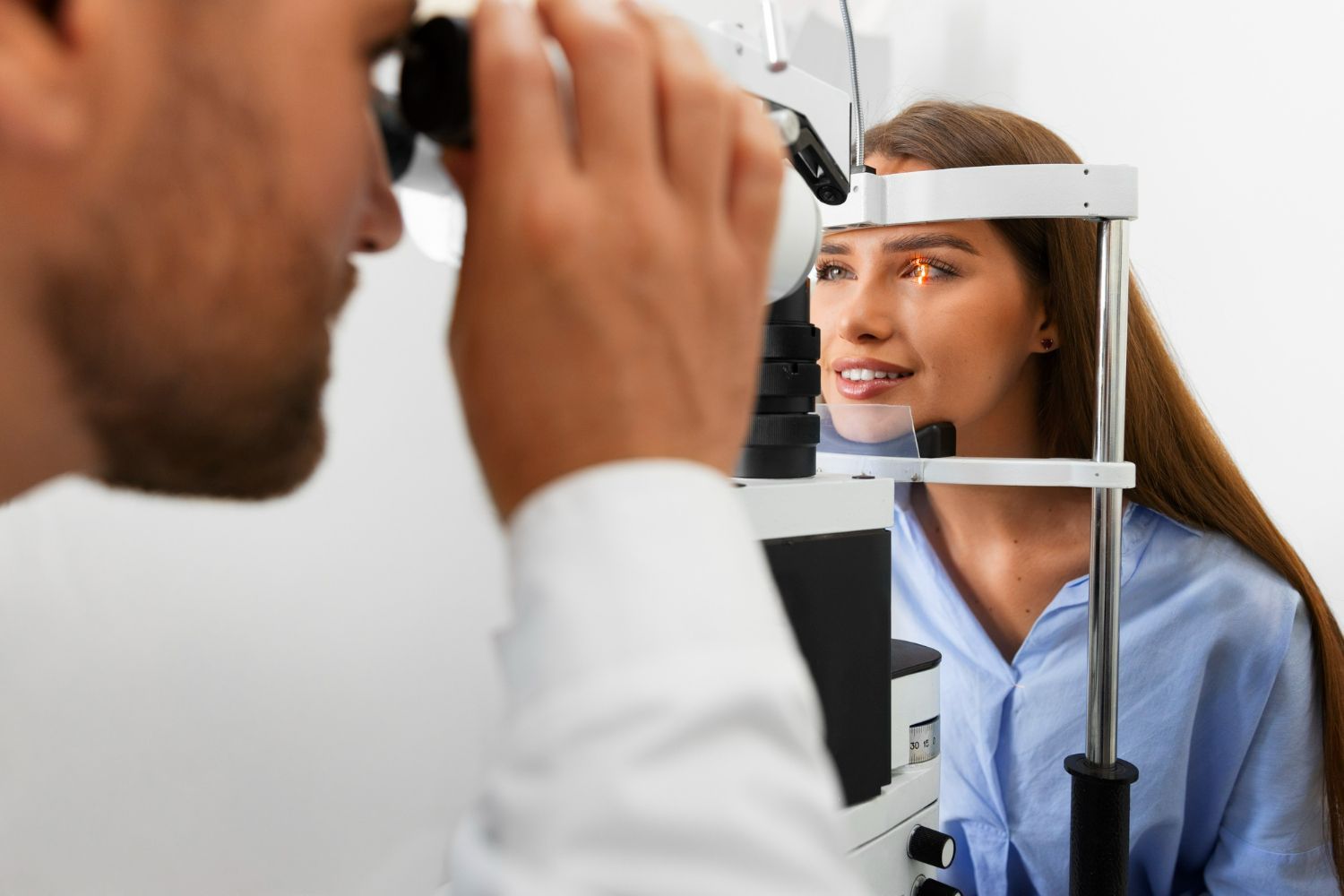 Optometrist examining a patient's eye with a slit lamp in a clinic.