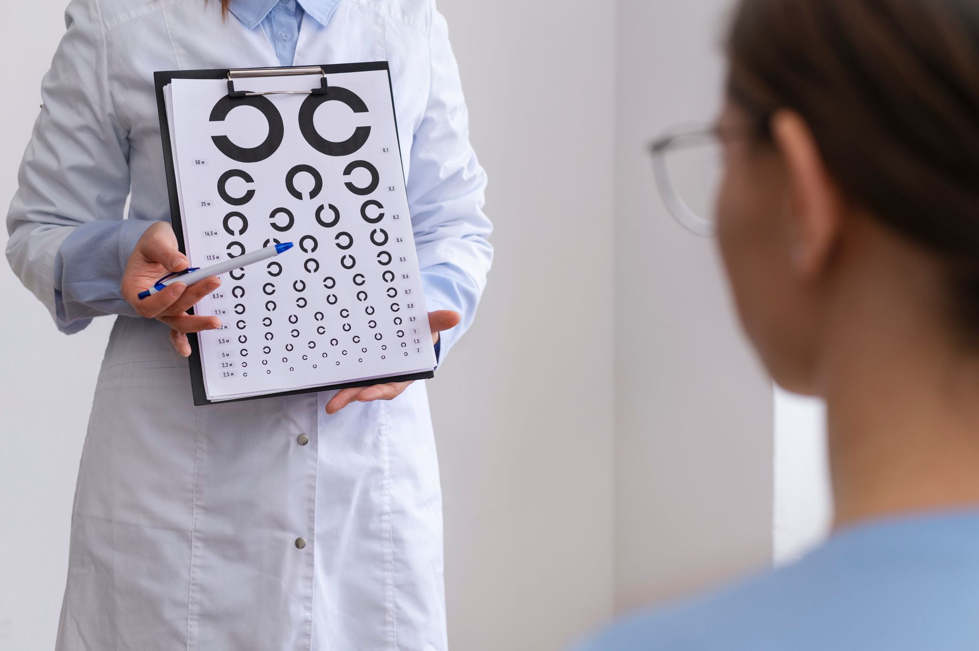 A doctor is holding a clipboard with a patient 's eye test on it.