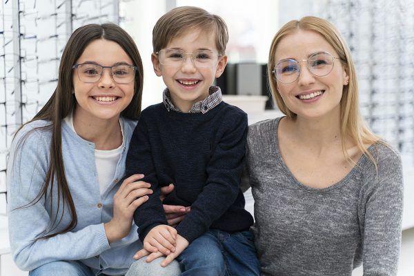 A woman and two children wearing glasses are posing for a picture.