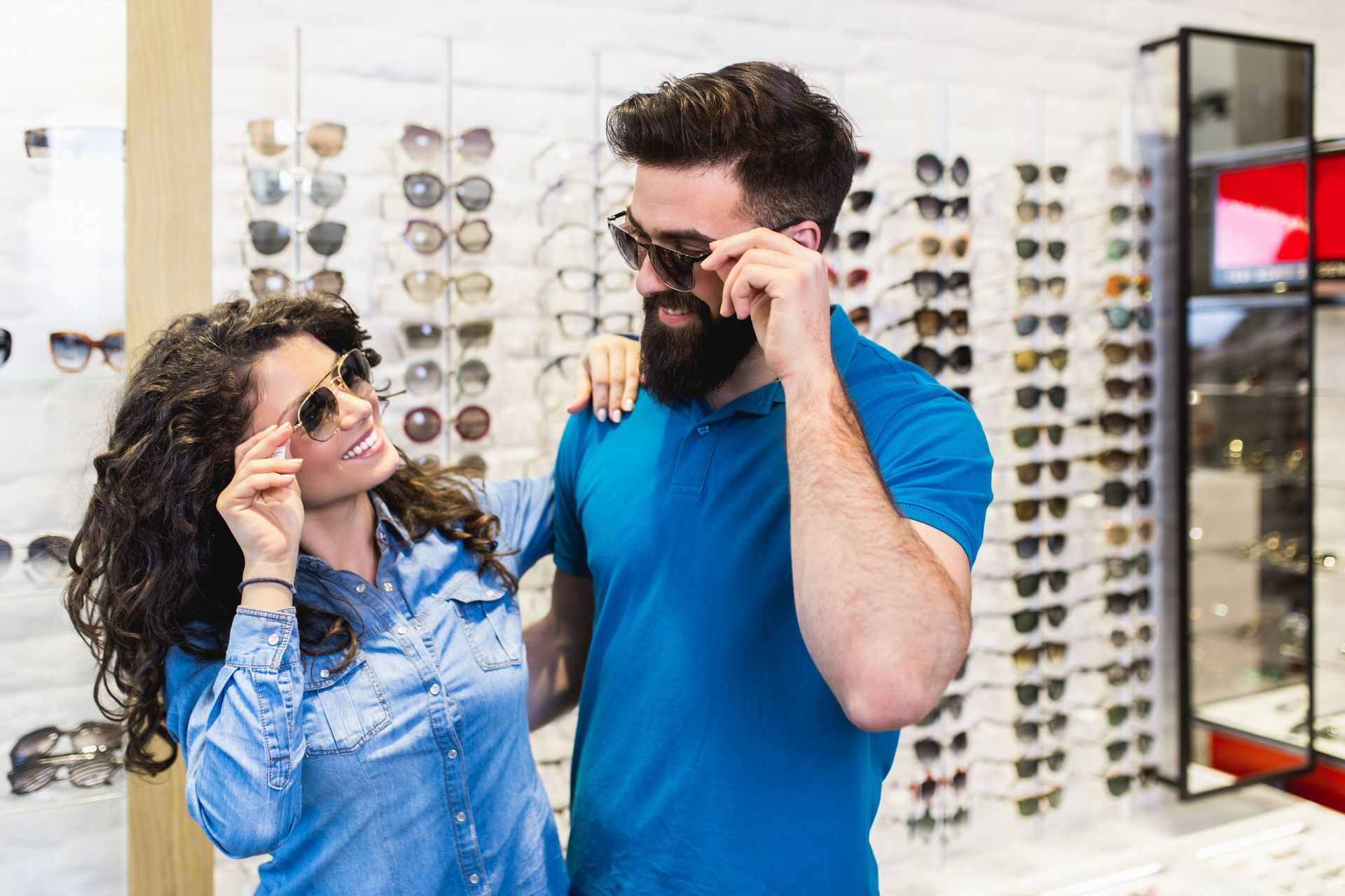 A man and a woman are trying on sunglasses in an optical shop.