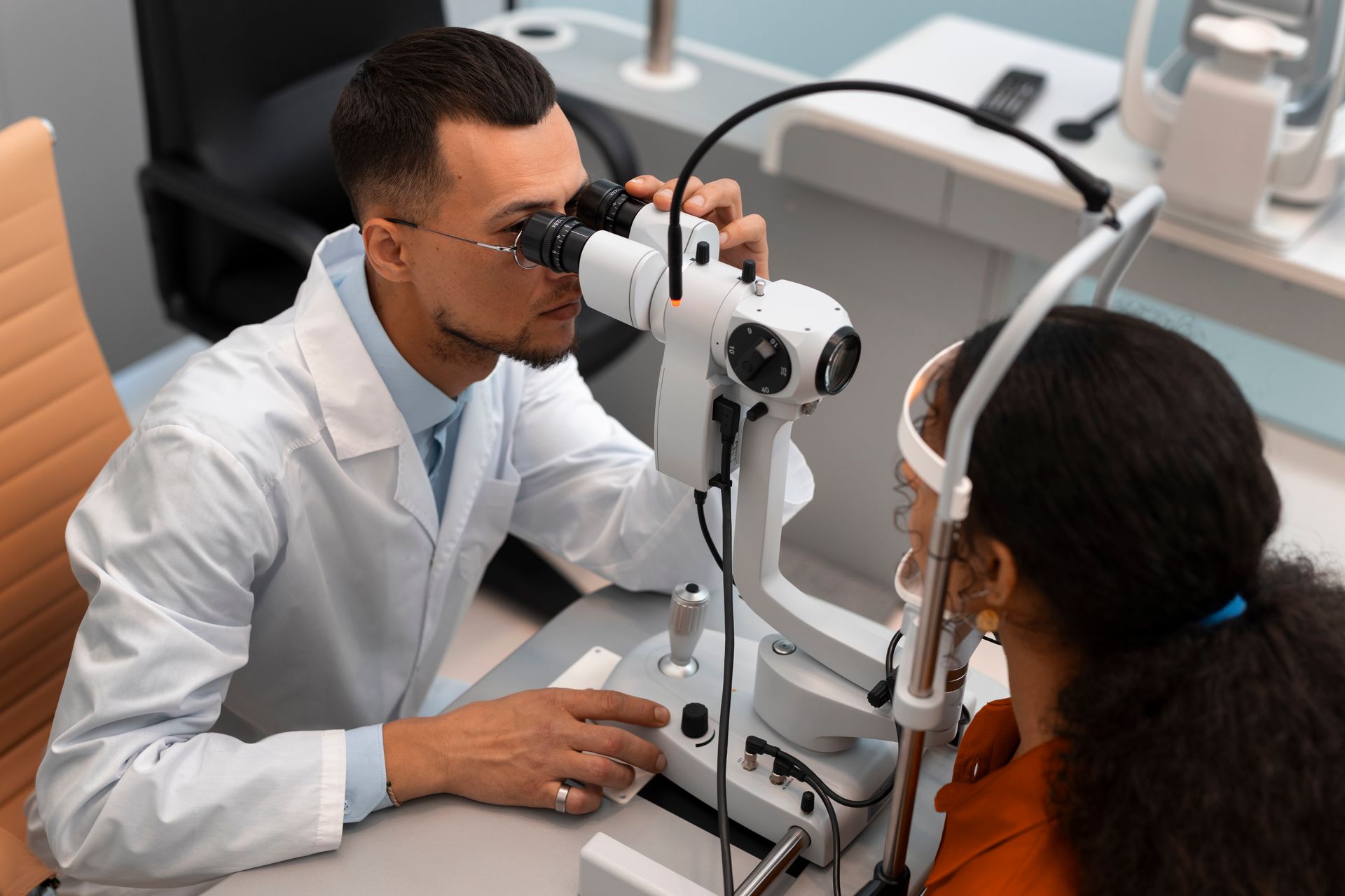An ophthalmologist is examining a patient 's eye with a microscope.