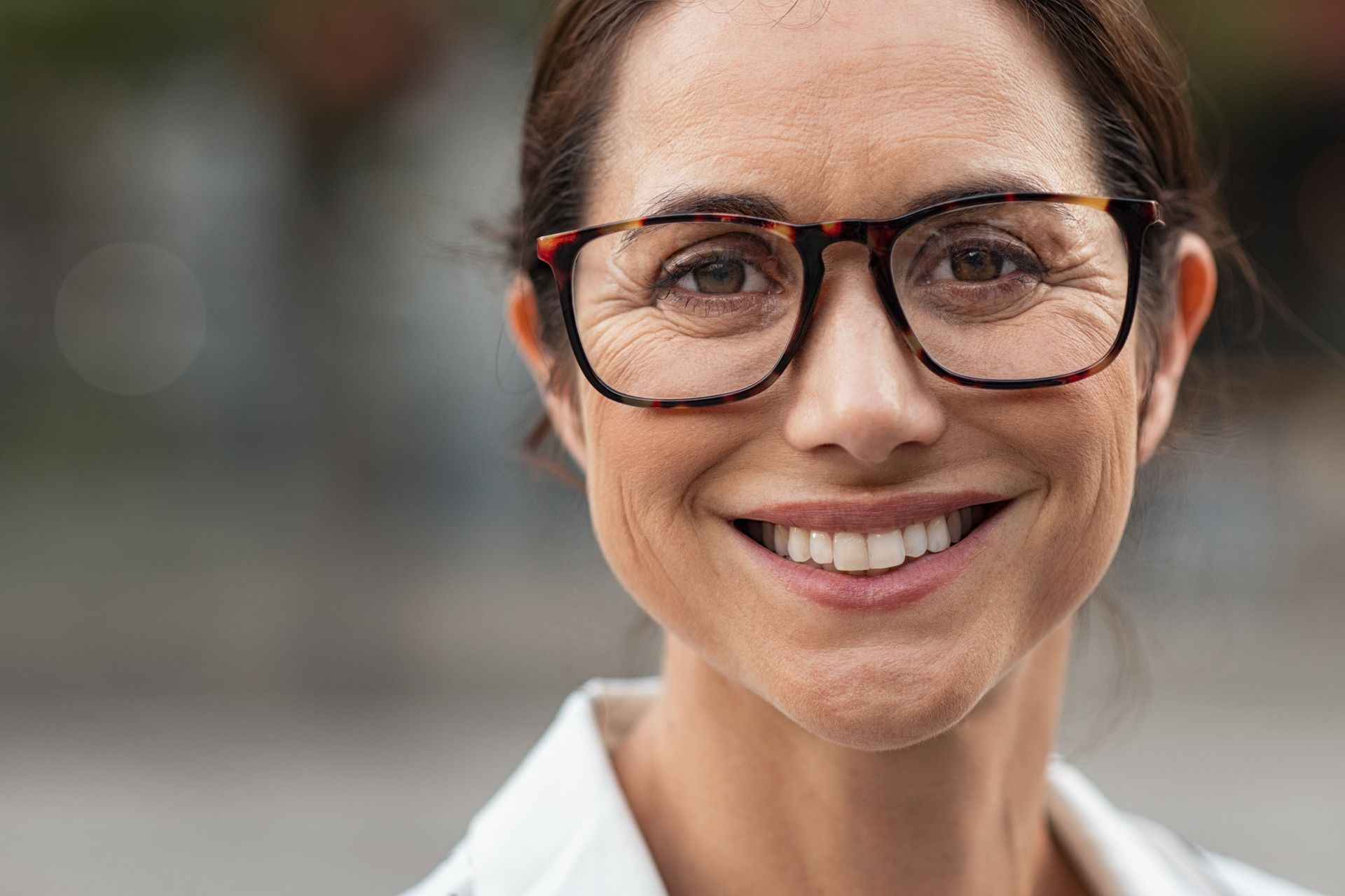 A close up of a woman wearing glasses and smiling.