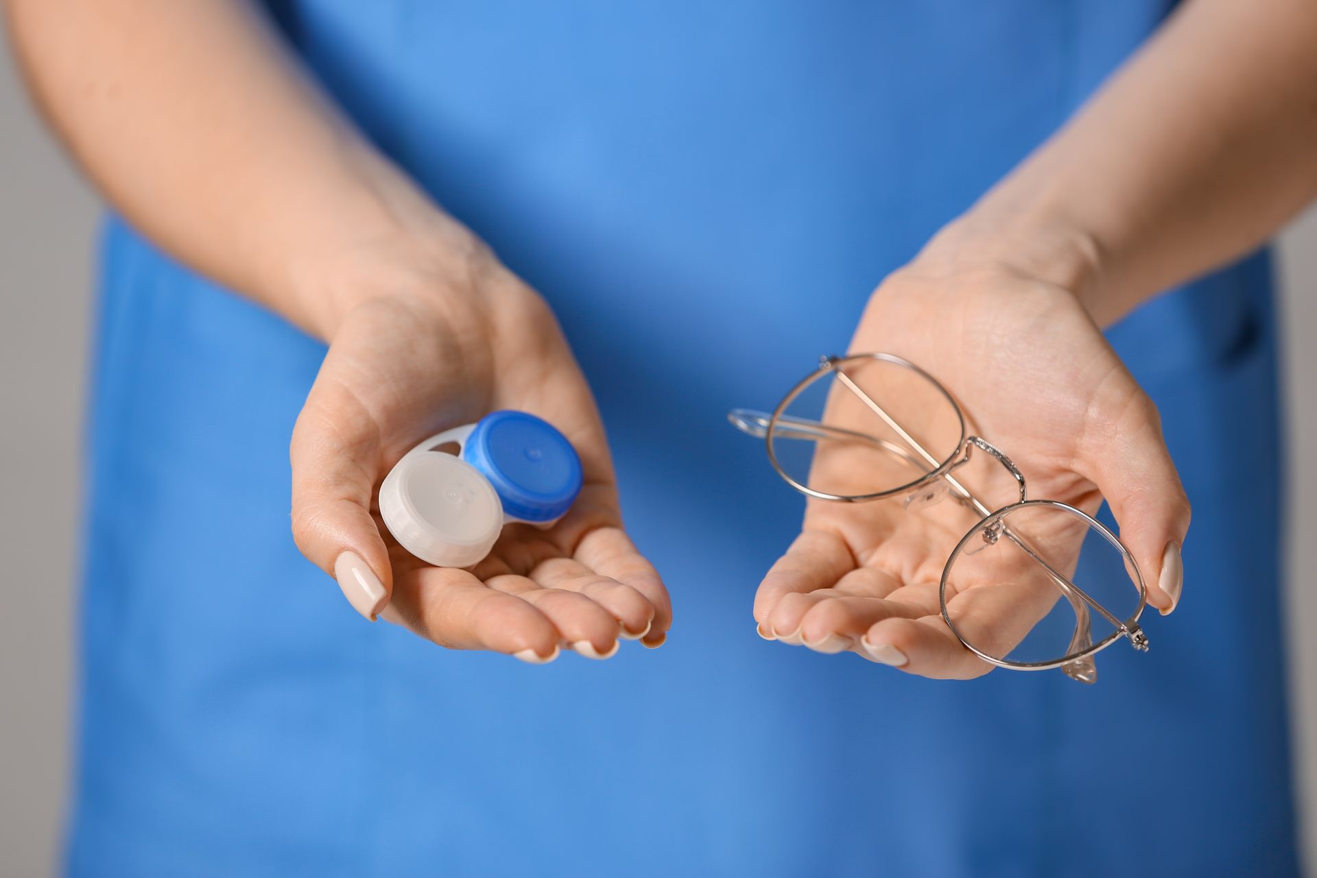 A woman is holding a pair of glasses and a contact lens case.