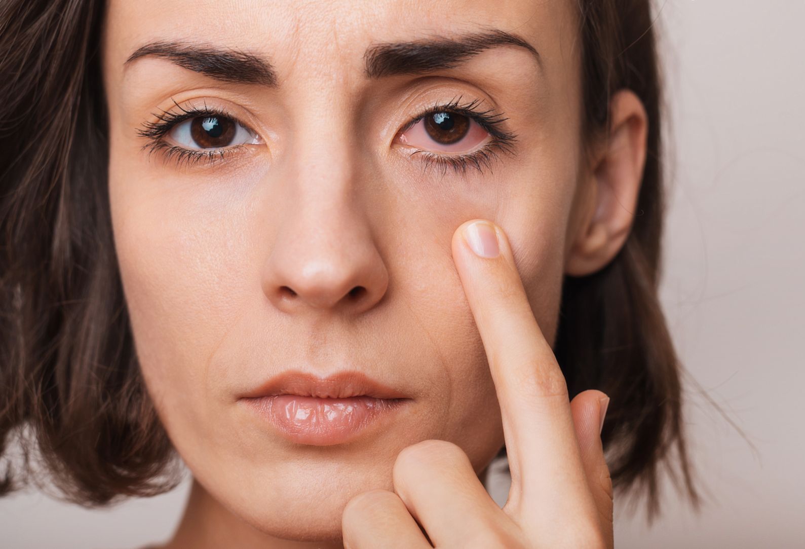 A woman is pointing at her eye with her finger.