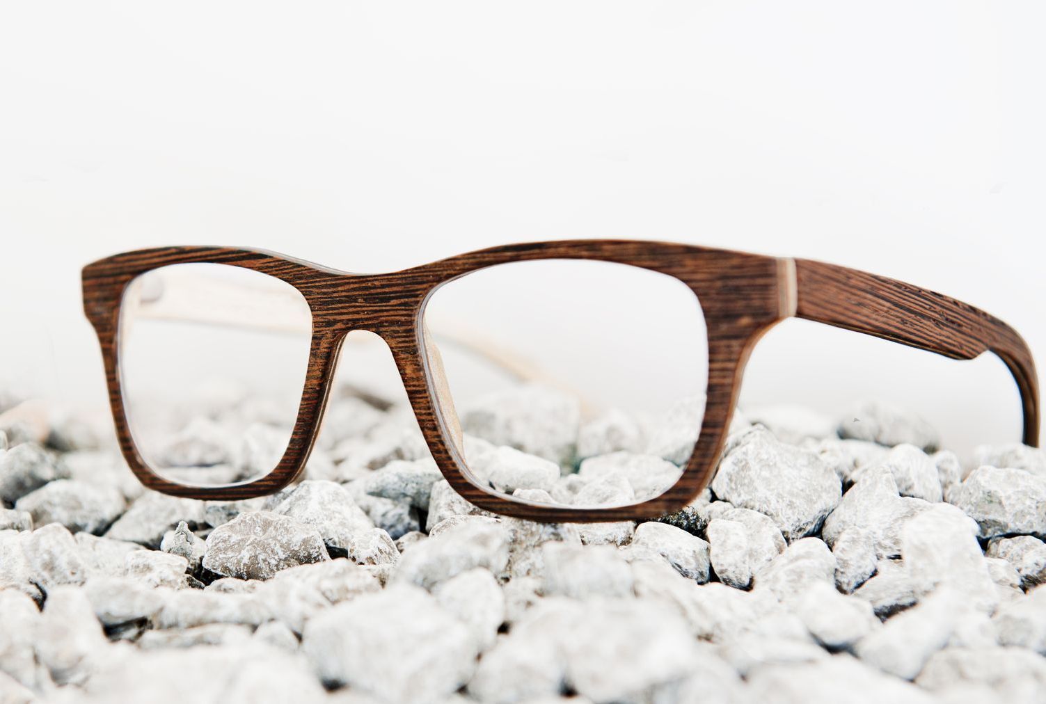 A pair of wooden glasses sitting on top of a pile of rocks.