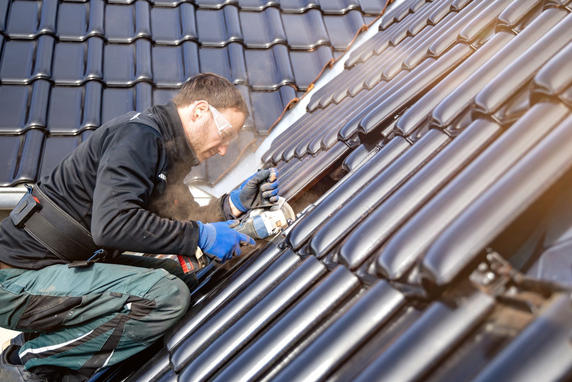 A man is kneeling on a roof working on a solar panel.