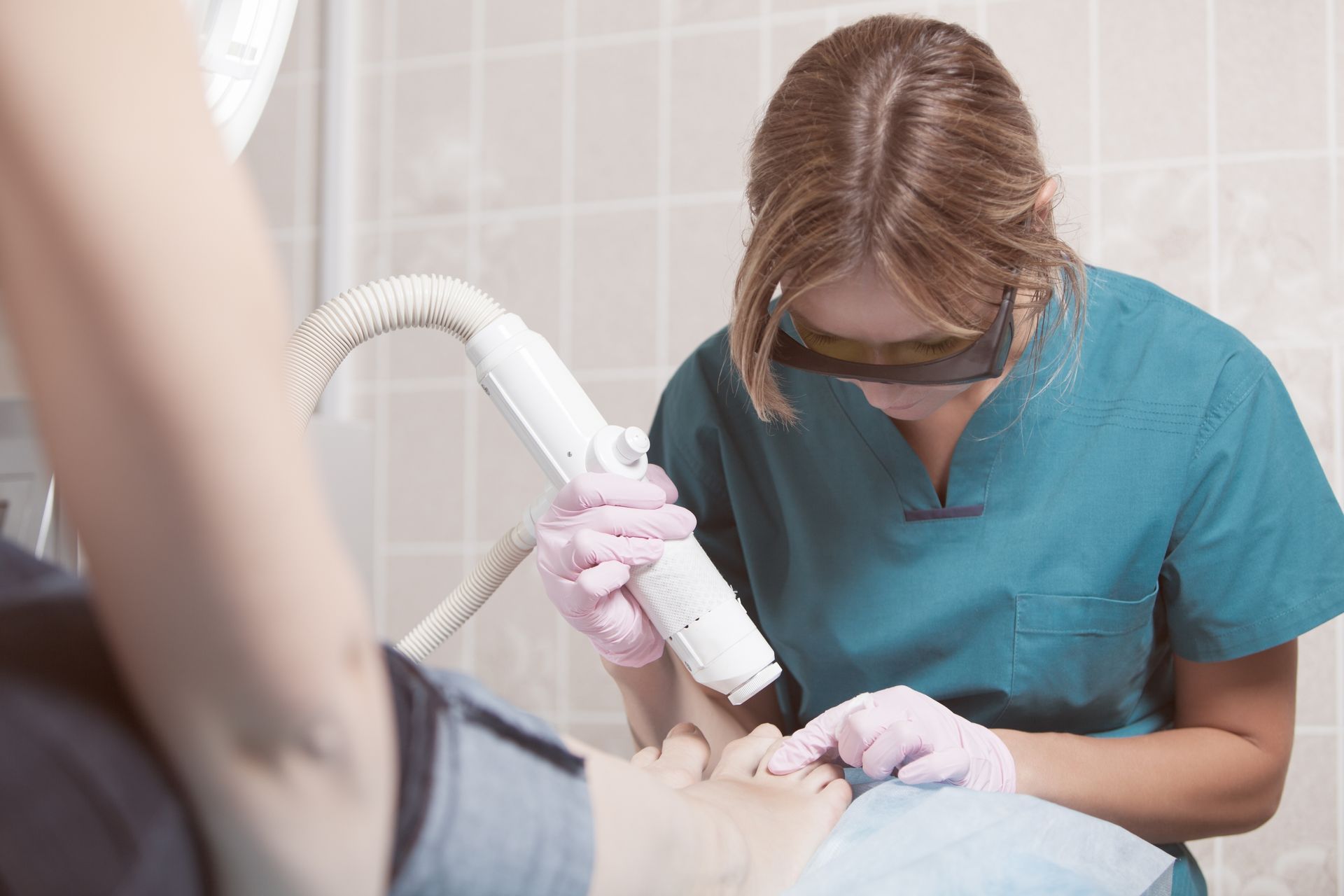 A woman is using a laser to remove hair from a patient 's face.