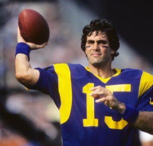 A man in a blue and yellow jersey with the number 15 throws a football. Vince Ferragamo