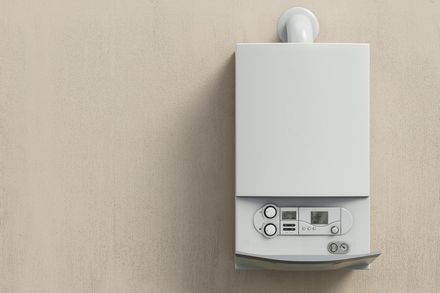 A white gas boiler installed on a white wall.
