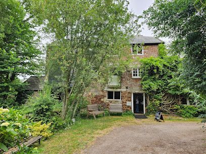 The entrance to a national trust property called Clyston Mill in Broadclyst, with trees surrounding the front door.