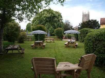 A beer garden behind a pub in Broadclyst with a view of the church in the background.