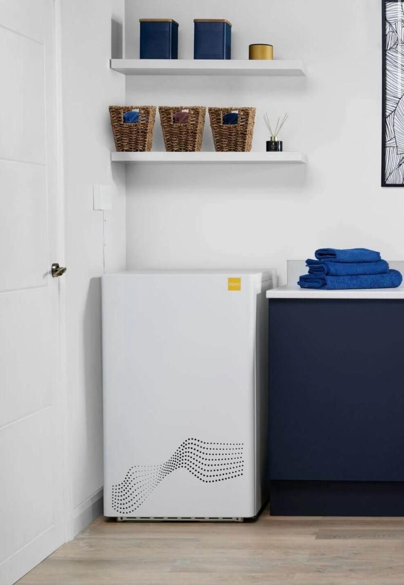 A white electric boiler, installed in the corner of a room.