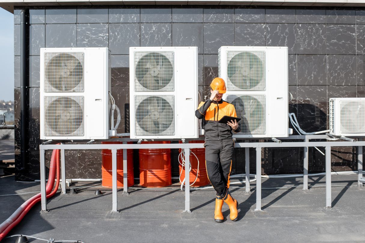 A man is standing in front of a row of air conditioners.