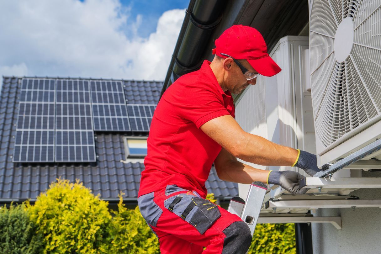 A man is working on an air conditioner outside of a house.