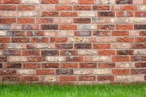 A brick wall with a patch of grass in front of it.