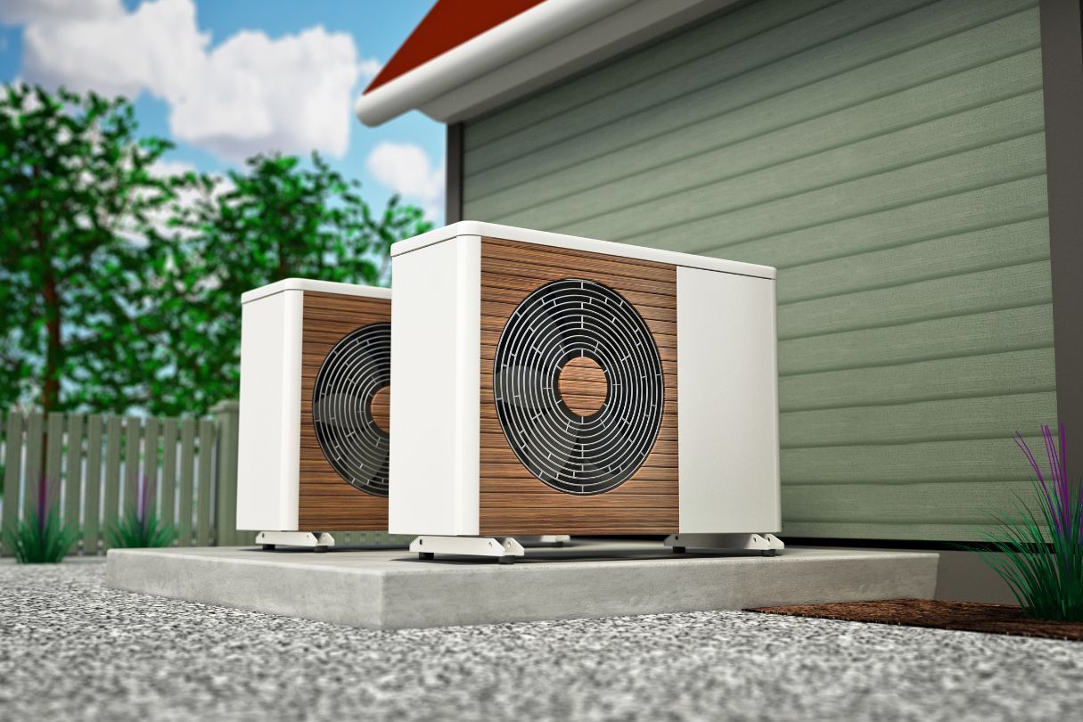 Two air conditioners are sitting outside of a house.