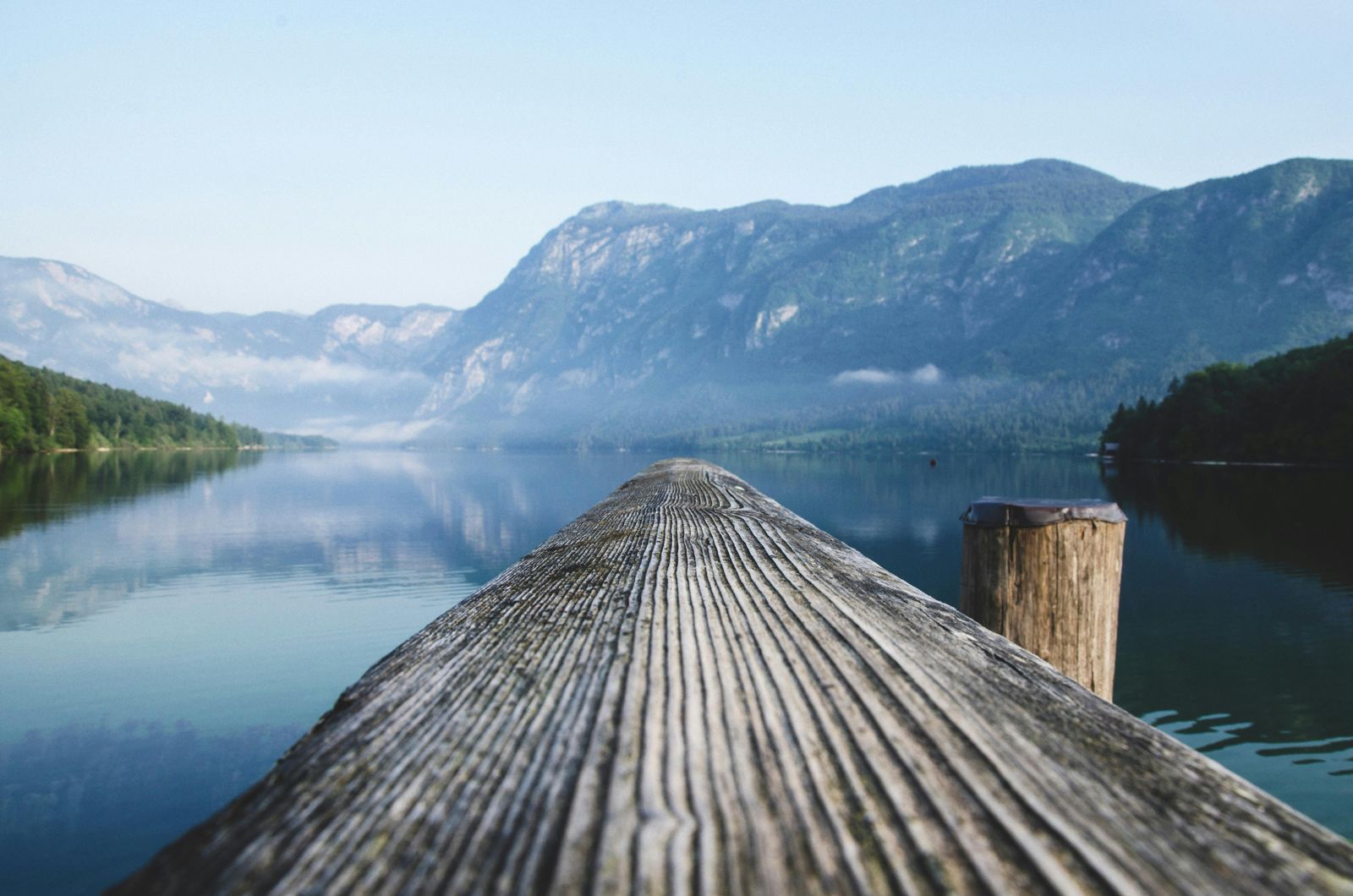 A wooden dock overlooking a lake with mountains in the background.