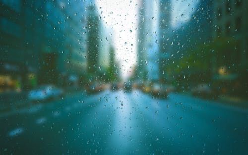 A blurry picture of a city street through a window with rain drops on it.