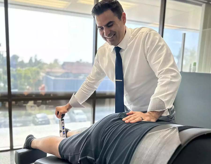 Chiropractor adjusting a patient’s lower back on a treatment table in a bright office