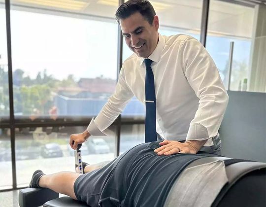 Chiropractor adjusting a patient’s lower back on a treatment table in a bright office