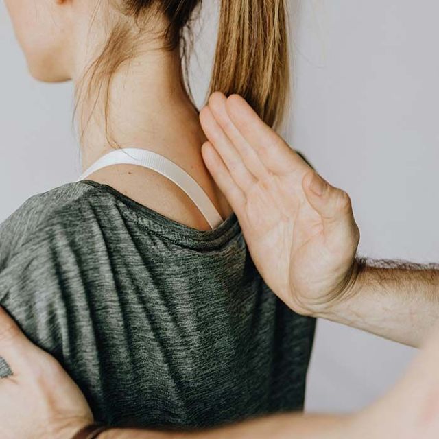 Physical therapist supporting a patient’s back during a manual treatment on a treatment table