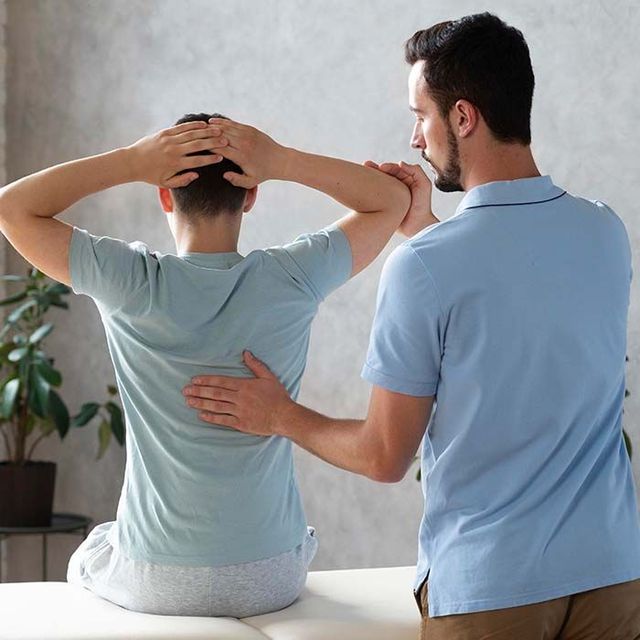 Physical therapist examining a seated patient with hands on head in a clinic