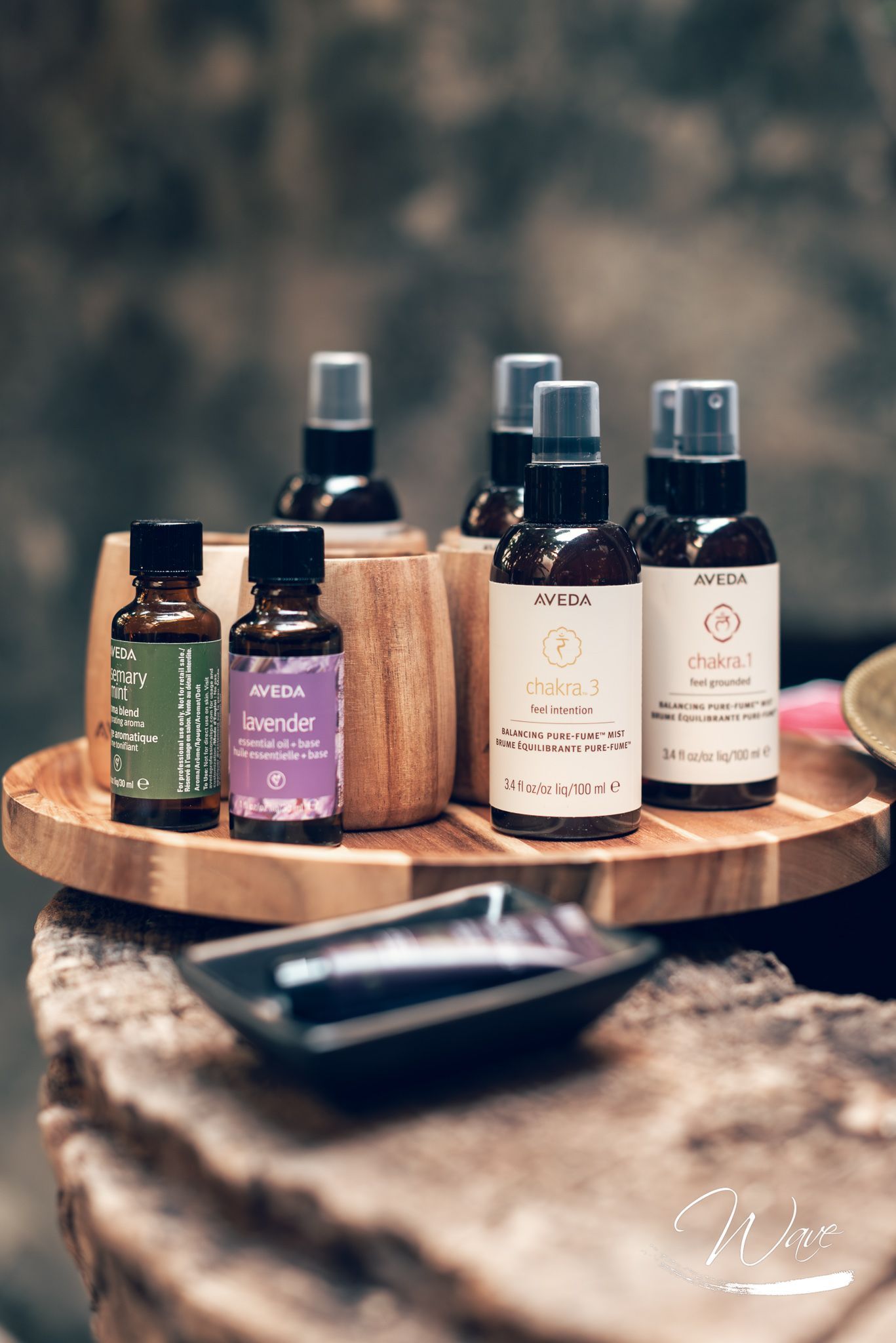 Esposizione di prodotti per la spa: oli, spray e creme su un vassoio di legno, in un ambiente buio.