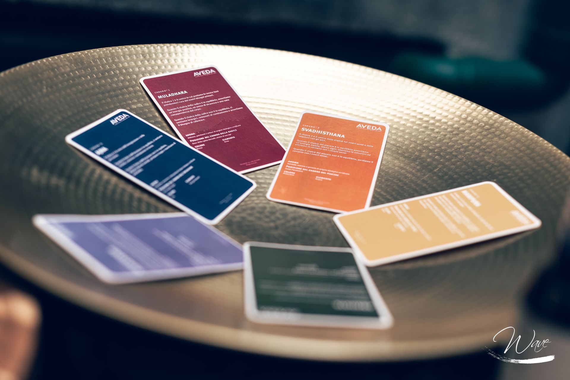 Sei carte colorate su un piatto dorato, angolate. Ognuna ha il testo bianco. Lo sfondo è sfocato.