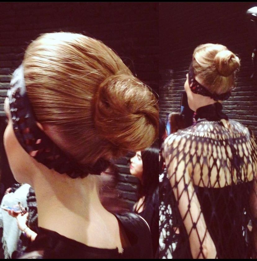 Models with buns and elaborate neckpieces, backstage.