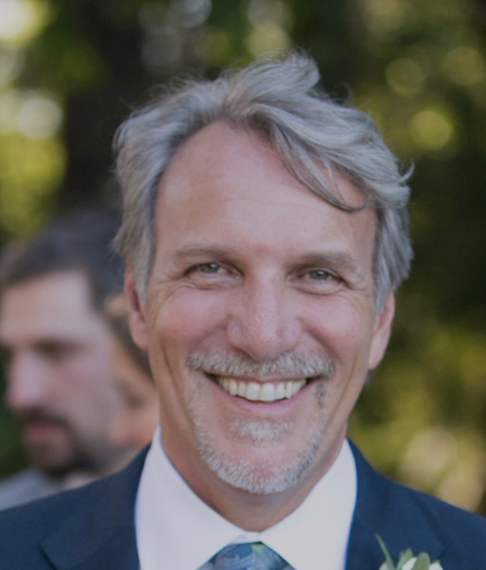 A man in a suit and tie is smiling for the camera