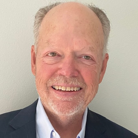 A man with a beard and a suit is smiling for the camera.