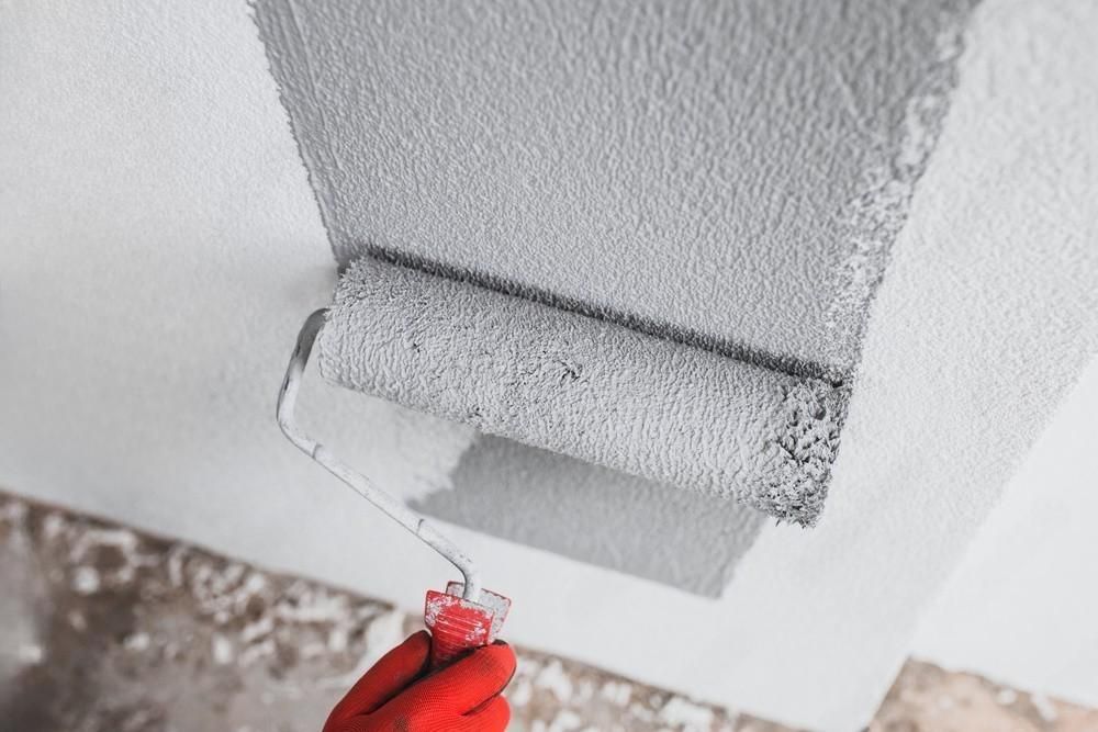 a person is painting a wall with a paint roller .