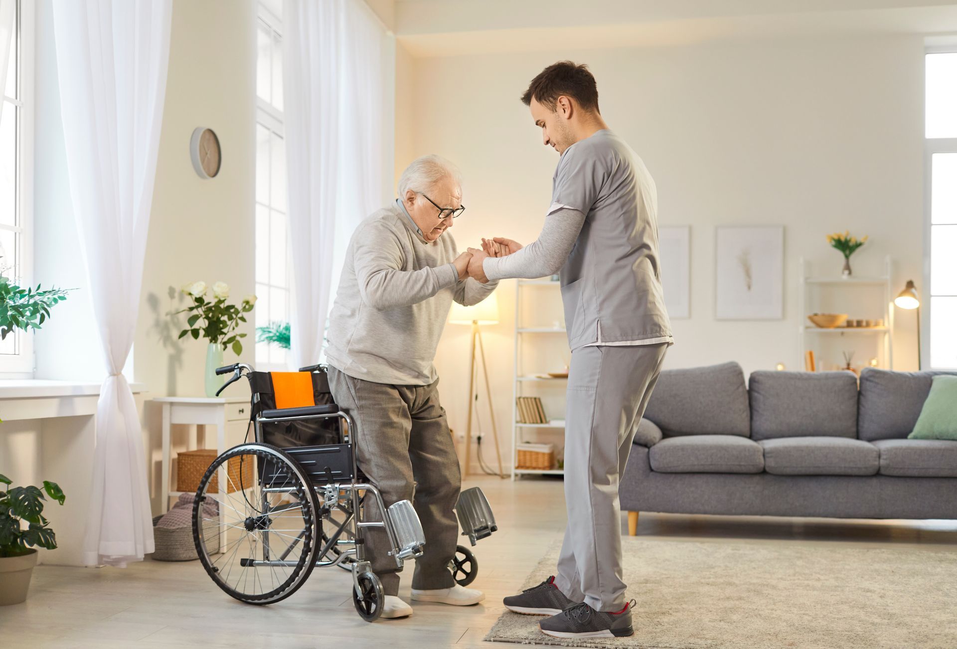 Smiling older Black man with a caregiver's hand on his shoulder, indoors.