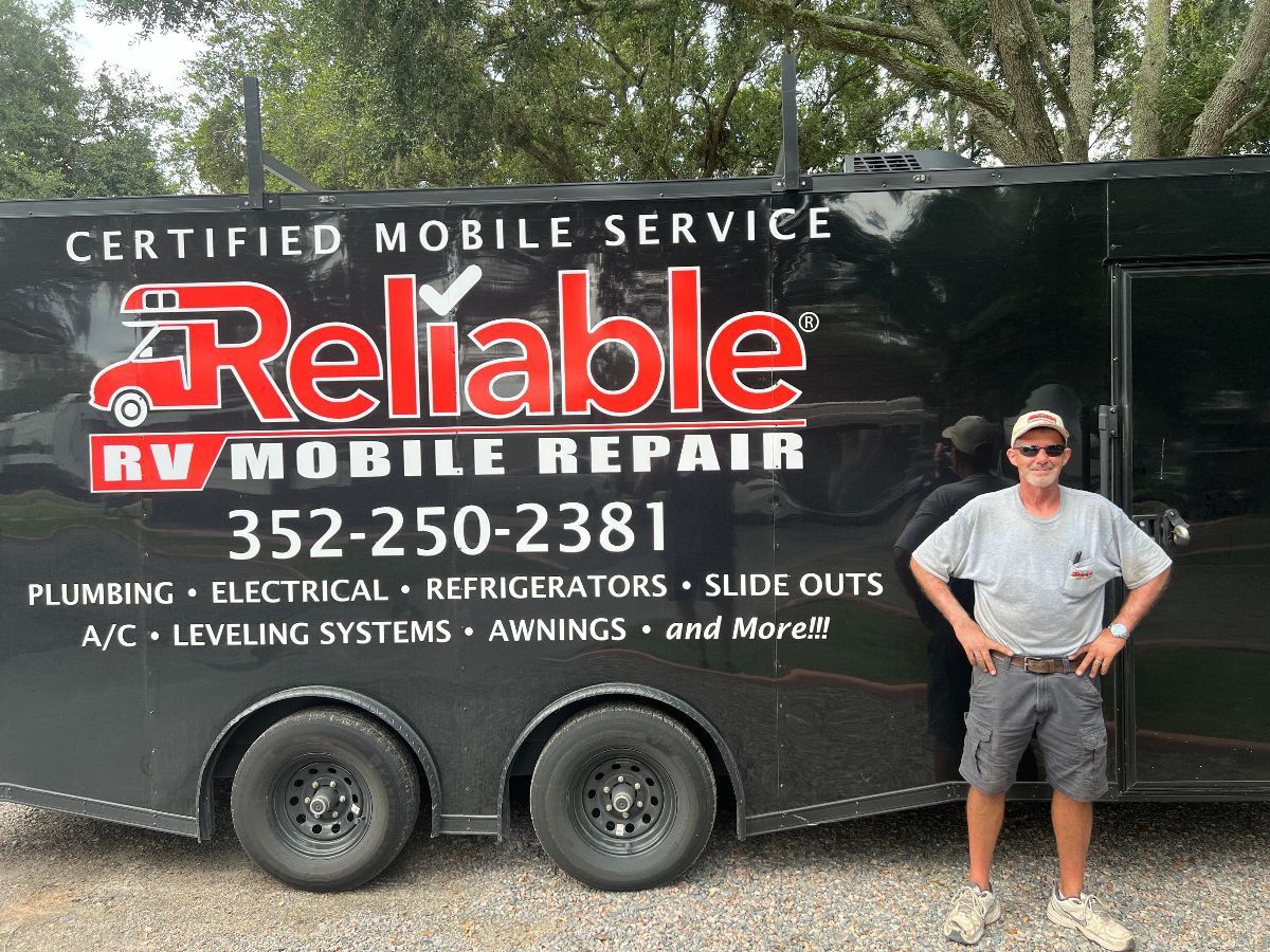 A man is standing in front of a reliable rv mobile repair trailer