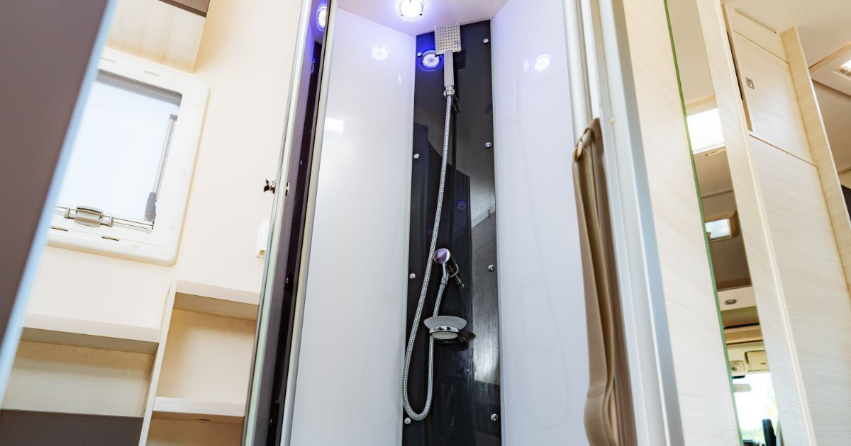 A bathroom in a camper van with a shower and a mirror.