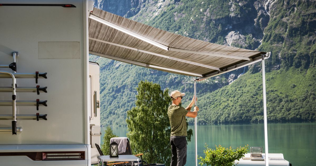 A man is installing an awning on the side of a rv.